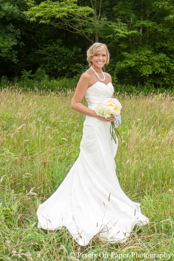 Bride in wedding dress and boots in field at outdoor country mountain wedding at big red barn in west jefferson nc photo