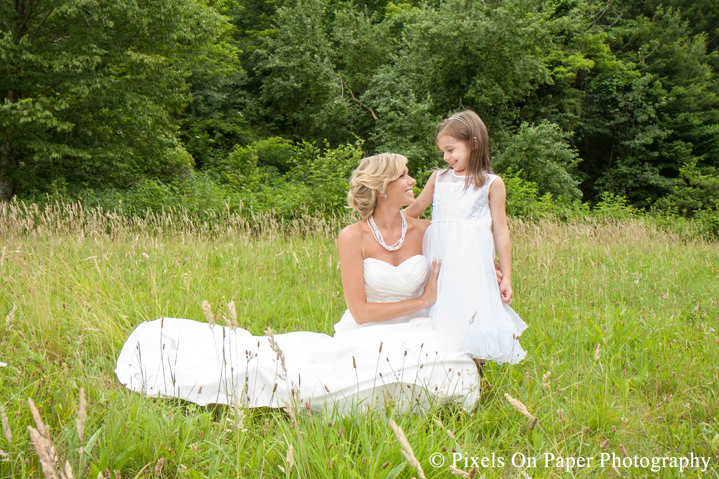Bride in wedding dress with daughter in field at outdoor country mountain wedding at big red barn in west jefferson nc photo