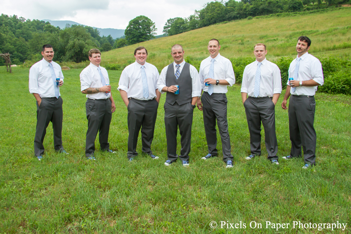 Groom and groomsmen in chuck tailors in field at outdoor country mountain wedding at big red barn in west jefferson nc photo