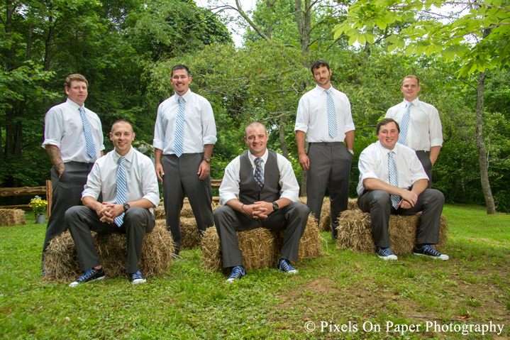 Groom and groomsmen on hay bails at outdoor country mountain wedding at big red barn in west jefferson nc photo