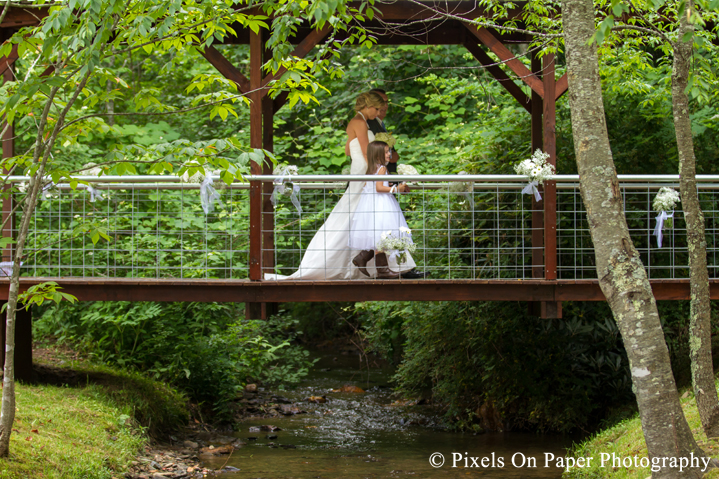 Bride walks covered bridge at outdoor country mountain wedding at big red barn in west jefferson nc photo