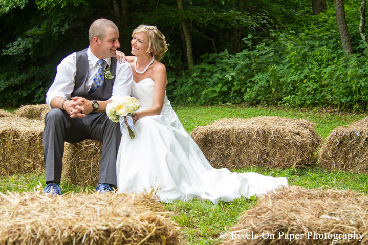 Bride and groom on hay bails for wedding photos at outdoor country mountain wedding at big red barn in west jefferson nc photo