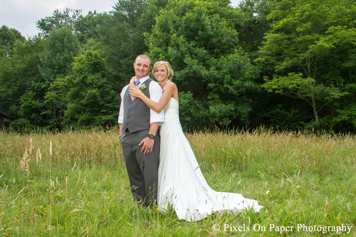 Bride and groom in field for wedding photos at outdoor country mountain wedding at big red barn in west jefferson nc photo