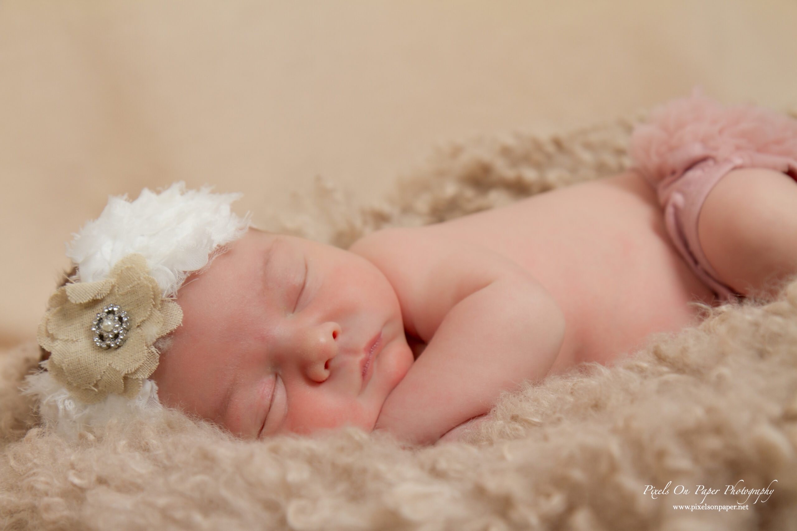 Lucy Roberts wearing a delicate floral headband, peacefully napping during her newborn portraits.