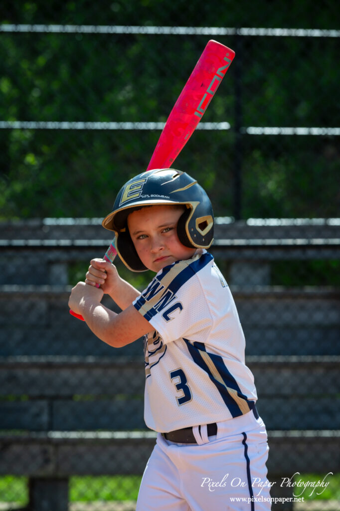 Young baseball player from NWNC Elite 8U posing with cap and glove on the field