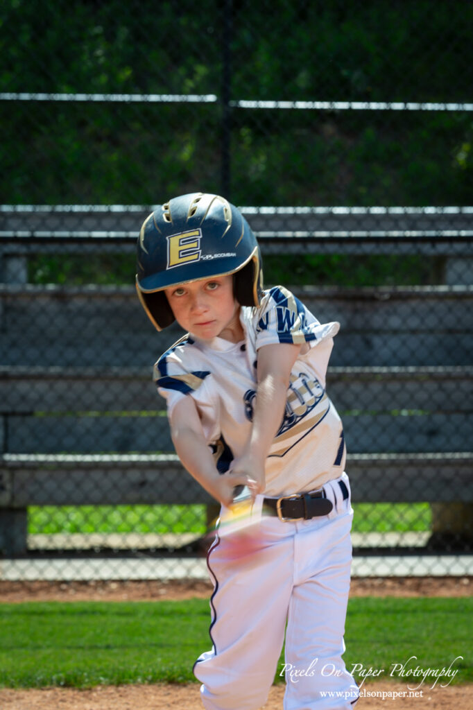 Close-up of NWNC Elite 8U player swinging bat during youth sports photography session.