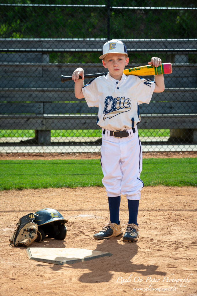 Young baseball player from NWNC Elite 8U posing with cap and glove on the field