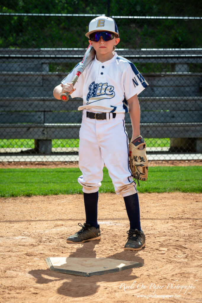 Young baseball player from NWNC Elite 8U posing with cap and glove on the field