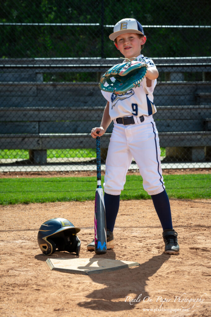 Young baseball player from NWNC Elite 8U posing with cap and glove on the field