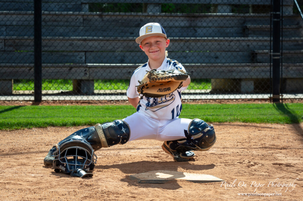 Young baseball player from NWNC Elite 8U posing with cap and glove on the field